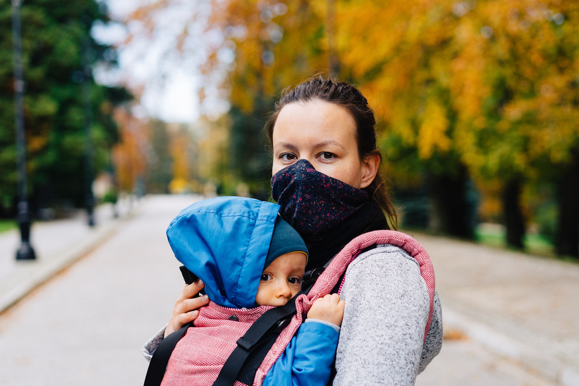 Woman wearing COVID-19 mask and holding a baby.