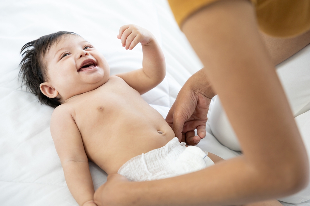 mom diapering smiling baby